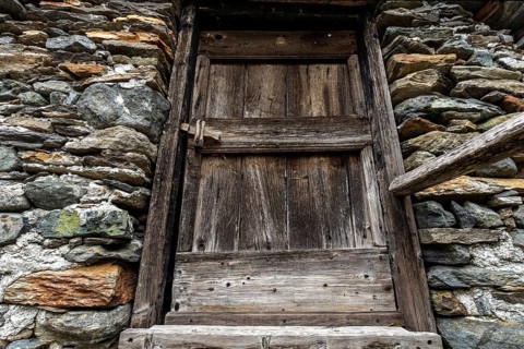 Old wooden door of a typical Ticino stone house in the mountain village of Bordei, Centovalli,