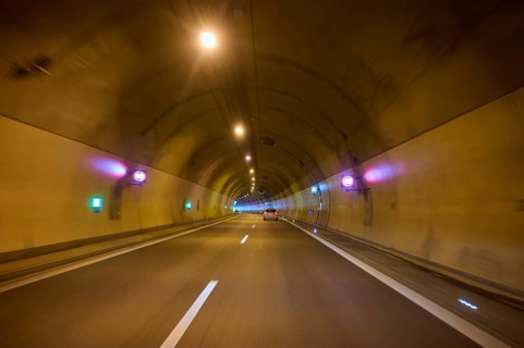 Illuminated motorway tunnel with several lights and signs, Switzerland, Europe