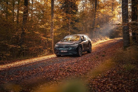 Car on a secluded forest path, surrounded by autumn leaves and golden light, electric car VW ID5,