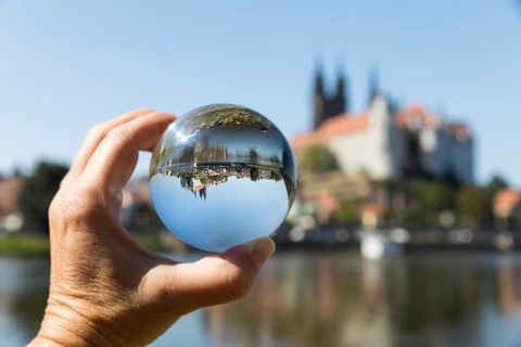 Hand holding a glass ball reflecting the typical city view with Albrechtsburg Castle, cathedral and