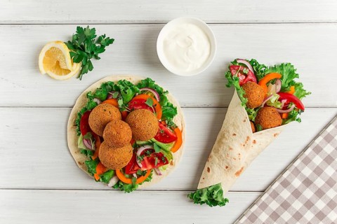Tortillas, wrapped falafel balls, with fresh vegetables, vegetarian healthy food, on a wooden white