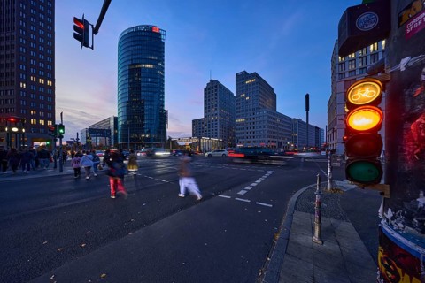 Cyclist traffic light, pedestrian crossing, pedestrian with motion blur and railway tower at blue
