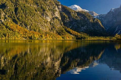 Lake Almsee in autumn with mountains reflected in the lake. Blue sky with no clouds
