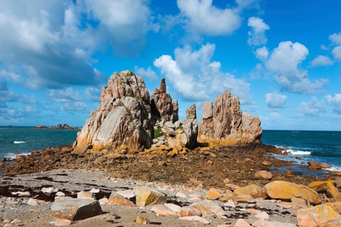 Rock formations on a sunny coast under a blue sky with clouds, Plage de Pors Scaff, Plougrescant,