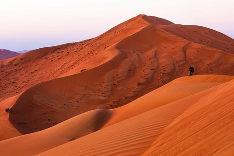A photographer with a tripod in the wind-sculpted sand dunes in the Rub al Khali desert, Dhofar