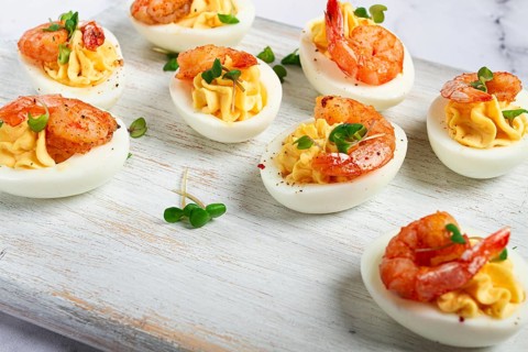 Boiled eggs stuffed with yolk and seasoned with mayonnaise, stuffed eggs with shrimp, on a white
