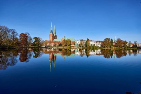 Long shot of the mill pond, trees, Lübeck Cathedral, general buildings, symmetrical reflections on