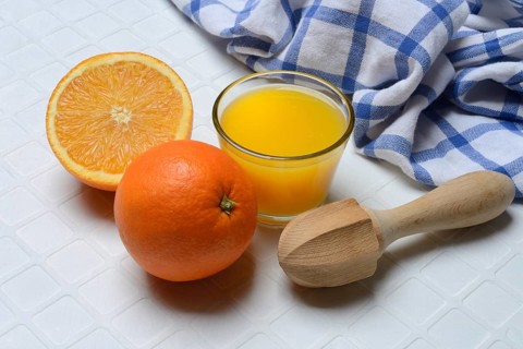 Orange juice in glass and orange, citrus juicer