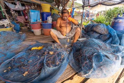 Fisherman repairing his net, fishing village Ban Ao Salad, island Ko Kut or Koh Kood in the Gulf of