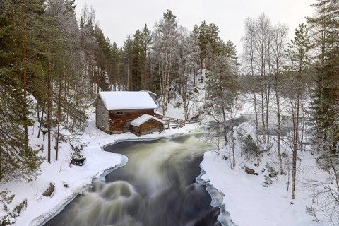 Old wooden Myllykoski water mill along the river Kitkajoki in winter, Oulanka National Park,