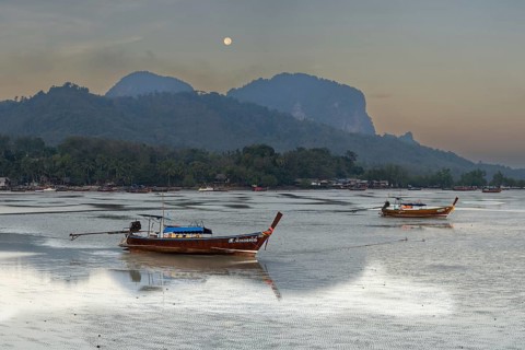 Before sunrise, longtail boats lie at low tide in the harbour at Sivalai Beach, Koh Mook Island,