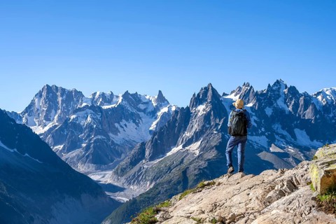 Mountaineer on a hiking trail in front of a mountain landscape, view of the mountain peaks Grandes