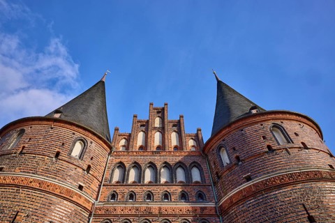 City gate, historic brick building, round towers with slate roof, gable, frog perspective,