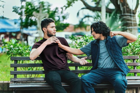 Two guys arguing sitting on a bench. Two male friends arguing on a park bench