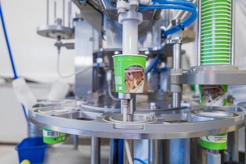 Industrial filling machine fills ice cream into green tubs, ice cream production Haselstaller Hof,