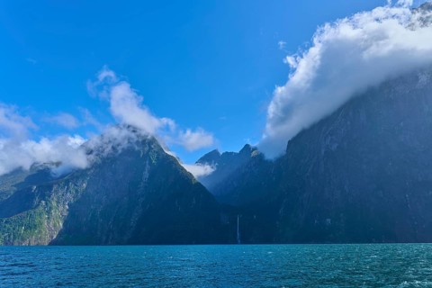 Twisted clouds envelop majestic mountains over the sea, fjord landscape, summer, Milford Sound, Te