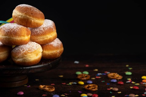 Doughnuts on a plate with scattered confetti and pretzels on a dark background