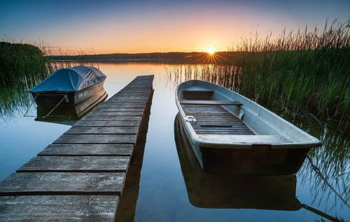 Quiet lake at sunset, rowing boats moored in the water at a wooden jetty, Gudelacksee, Lindow,