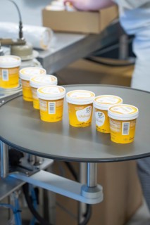 Filled yellow ice cream cups on a turntable in production, ice cream production Haselstaller Hof,