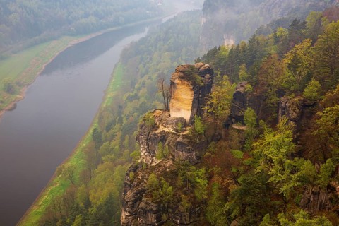 The bright lit Wartturm above the Elbe river seen from the Bastei rocks near the village of Rathen
