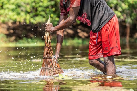 Fisherman pushing his basket with force into the water to the ground for catching fish with his