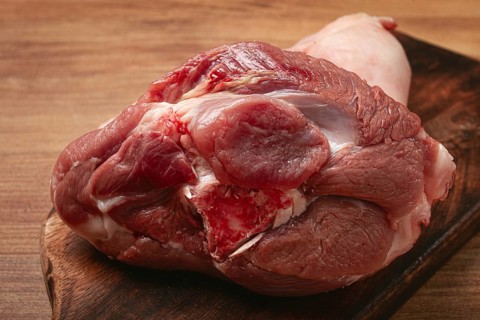 Raw pork knuckle, on a wooden chopping board, close-up, top view, no people