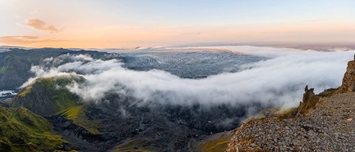 Fog between the cliffs, clouds moving around, glacier ice of the Kötlujökull glacier tongue at