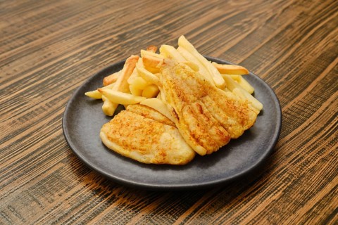 A plate holds two golden-brown pieces of fried fish alongside a generous serving of crispy french