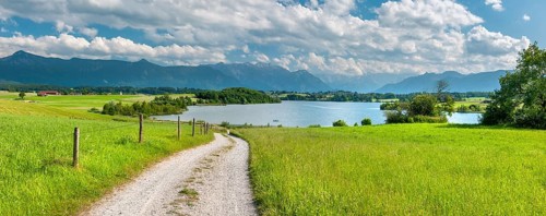 Field path leads through the countryside near Aidling, view of Lake Riegsee, Zugspitze in the