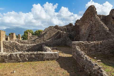 Old stone wall structures of varying heights and remnants of residential buildings at the ancient