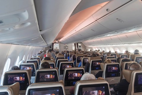 Etihad airline aircraft, interior, rows of seats with passengers. Boeing 787 aircraft on a flight