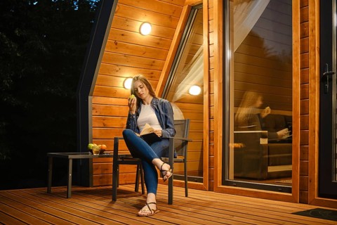 A young woman reads a book outdoors before bed while sitting on the terrace of a country house