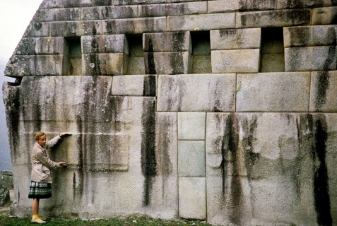 Tourists standing in front of huge stone blocks used for Inca masonry, Machu Picchu, Peru, South