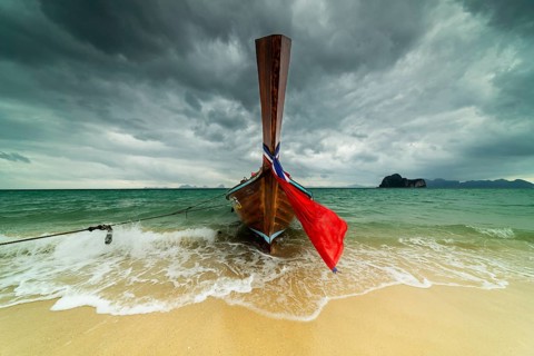 Longtail boat on the beach, dark rain clouds behind, Koh Ngai Island, Andaman Sea, Satun Province,