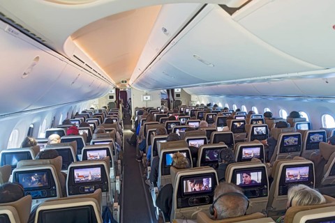 Etihad airline aircraft, interior, rows of seats with passengers. Boeing 787 aircraft on a flight