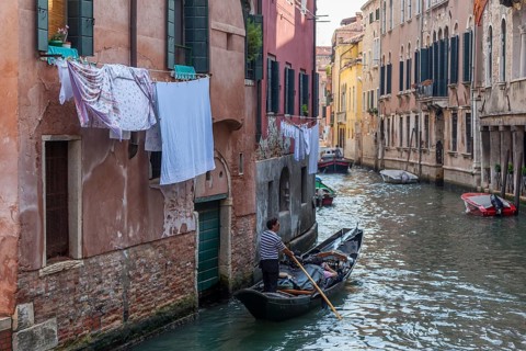 Narrow Venetian canal with boat in the foreground and laundry hanging to dry, Venice, Italy, Europe