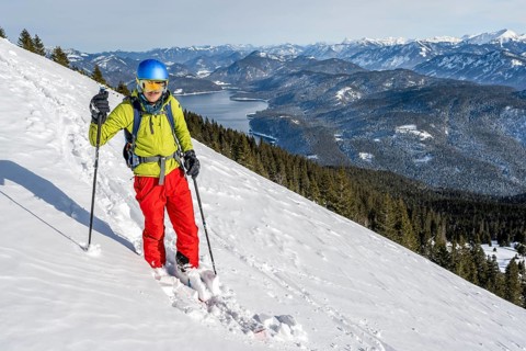 Skiers skiing down the Simetsberg, view of Walchensee and mountain panorama, Estergebirge, Bavarian