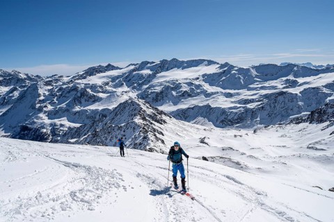 Mountain panorama with snow-covered mountain landscape, ski tourers climbing to the