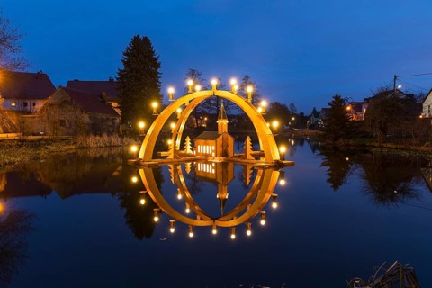 Floating double candle arch from the Ore Mountains with a model of the church on the village pond