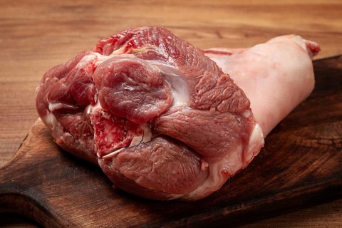 Raw pork knuckle, on a wooden chopping board, close-up, top view, no people