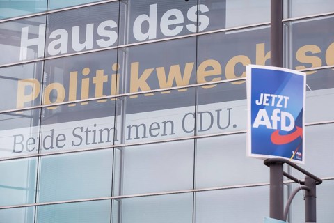 An election poster for the far-right AfD party (now AfD) hangs in front of a large banner with the