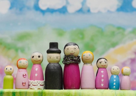 Nine funny painted wooden cones man and woman large and small in front of a colourful painted