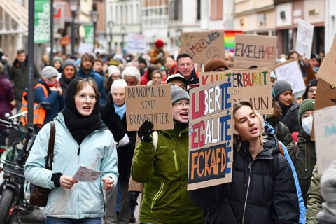 Heidelberg, Germany - February 12th 2025: Young people holding up signs in crowd at protest against