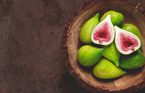 Fresh green figs, in a wooden plate, top view, close-up, no people