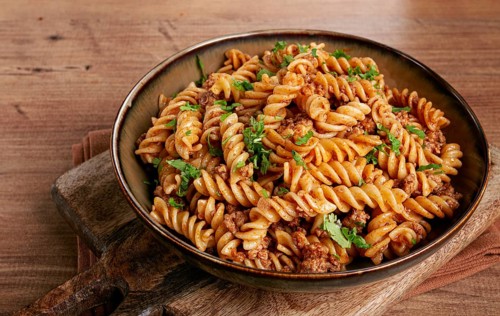 Pasta in the navy, pasta with minced meat, plate on a wooden table, homemade, fusilli pasta,