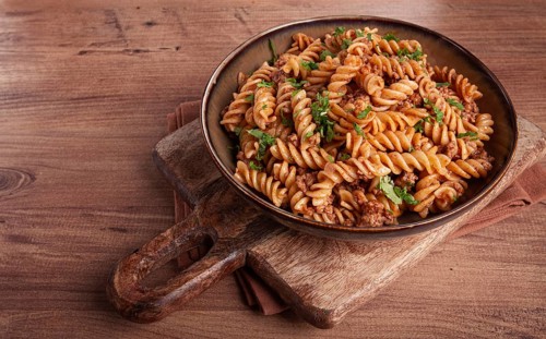 Pasta in the navy, pasta with minced meat, plate on a wooden table, homemade, fusilli pasta,