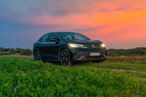 A car stands in front of a dramatic sunset in a field with a colourful sky, electric car, VW ID5,