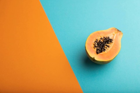 Ripe cut papaya on orange and blue pastel background. Side view, copy space. Tropical, healthy