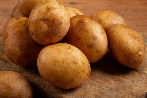 Raw potatoes, scattered on a chopping board, close-up, no people