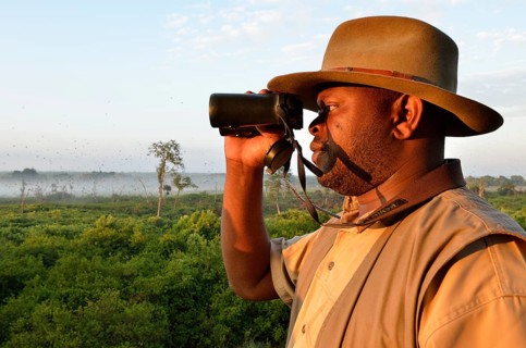 Local man looking through binoculars, Kasanka National Park, Zambia, Africa